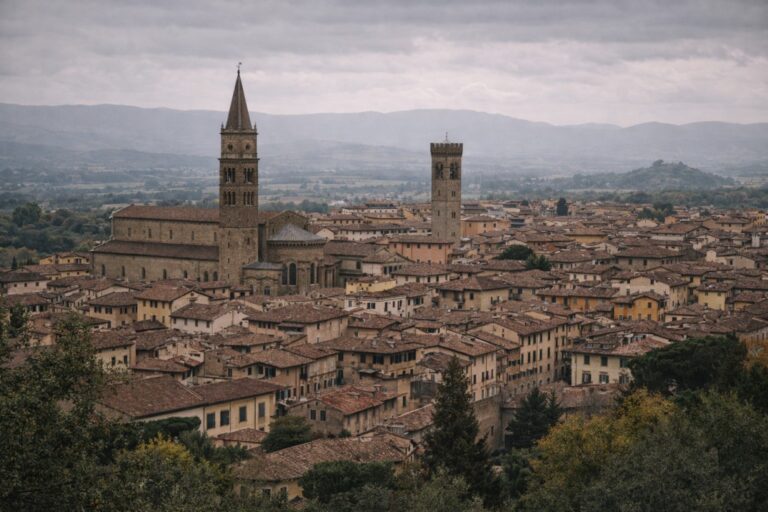 Arezzo skyline with cathedral bell tower and terracotta rooftops under overcast light.