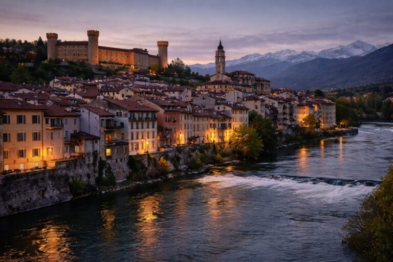 Ivrea town along the Dora Baltea river with castle and Alps at dusk