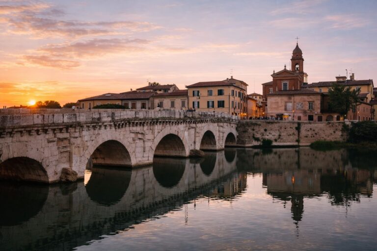 Ponte di Tiberio in Rimini over the Marecchia river at sunset with historic center in background