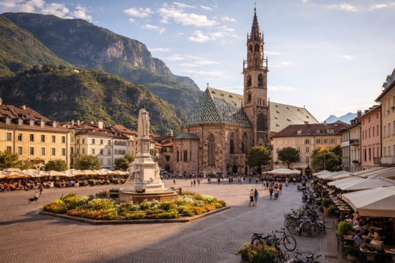 Piazza Walther in Bolzano with the Gothic Bolzano Cathedral and its patterned roof set against alpine mountains.