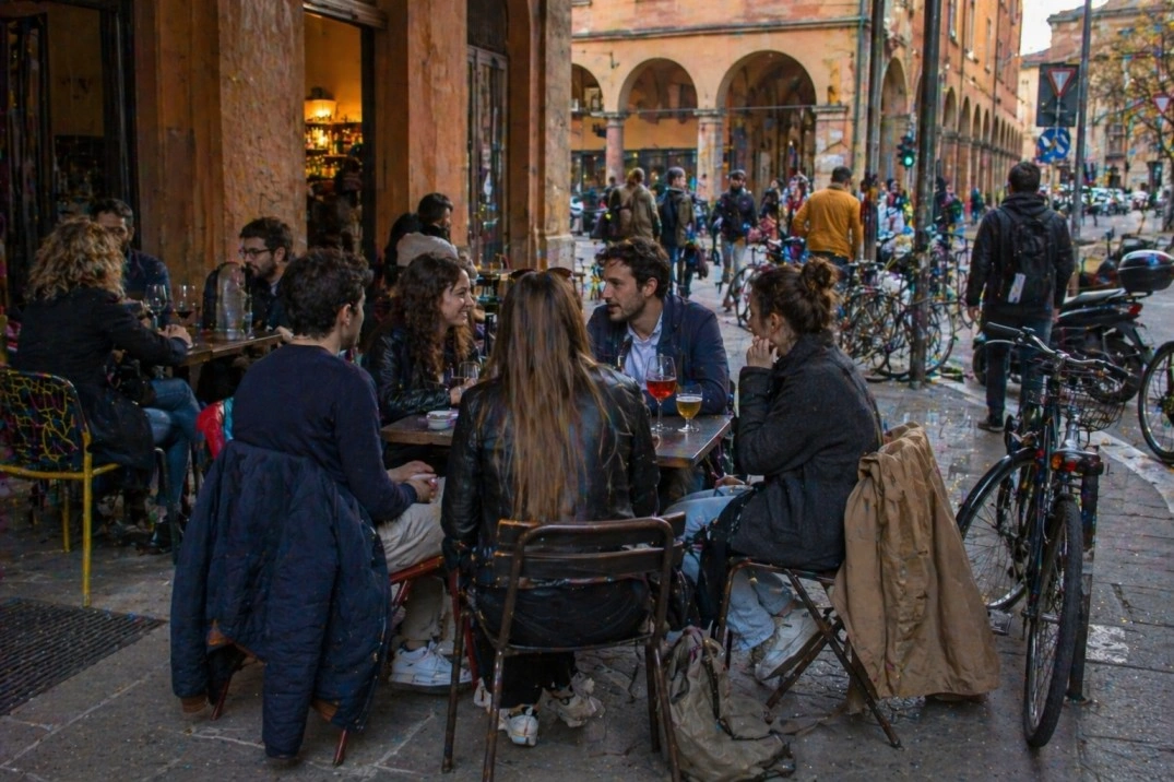 Community in Bologna, Italy – small group talking at an outdoor bar table