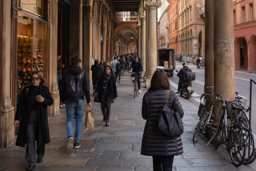 Living in Bologna, Italy – people walking under central porticoes on a normal day