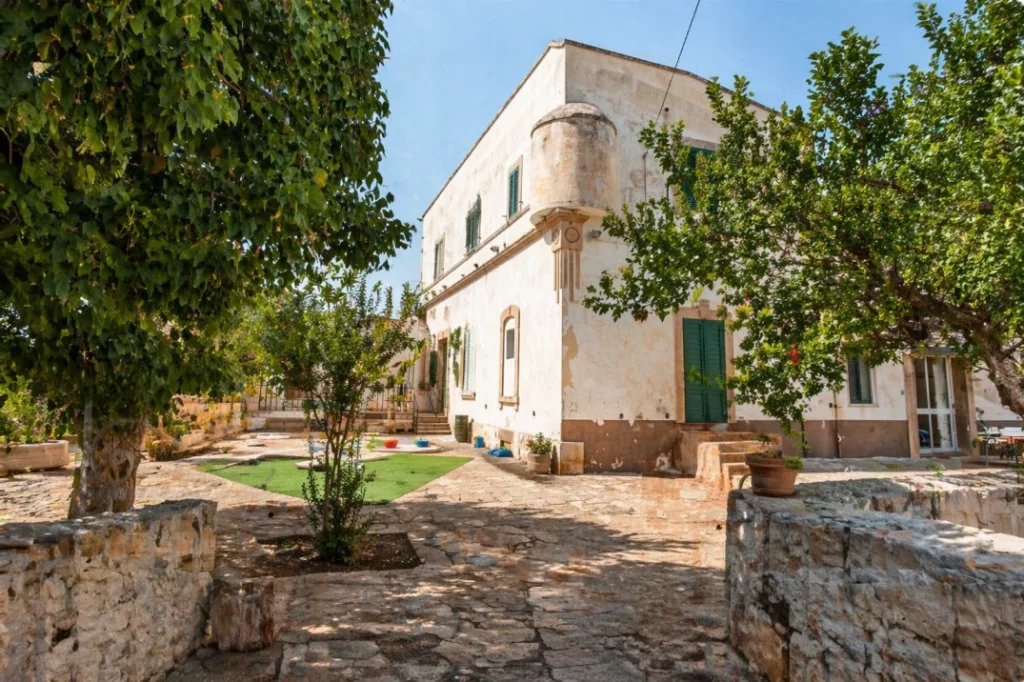 Masseria Olga coliving in Puglia courtyard with traditional white building, green shutters and garden