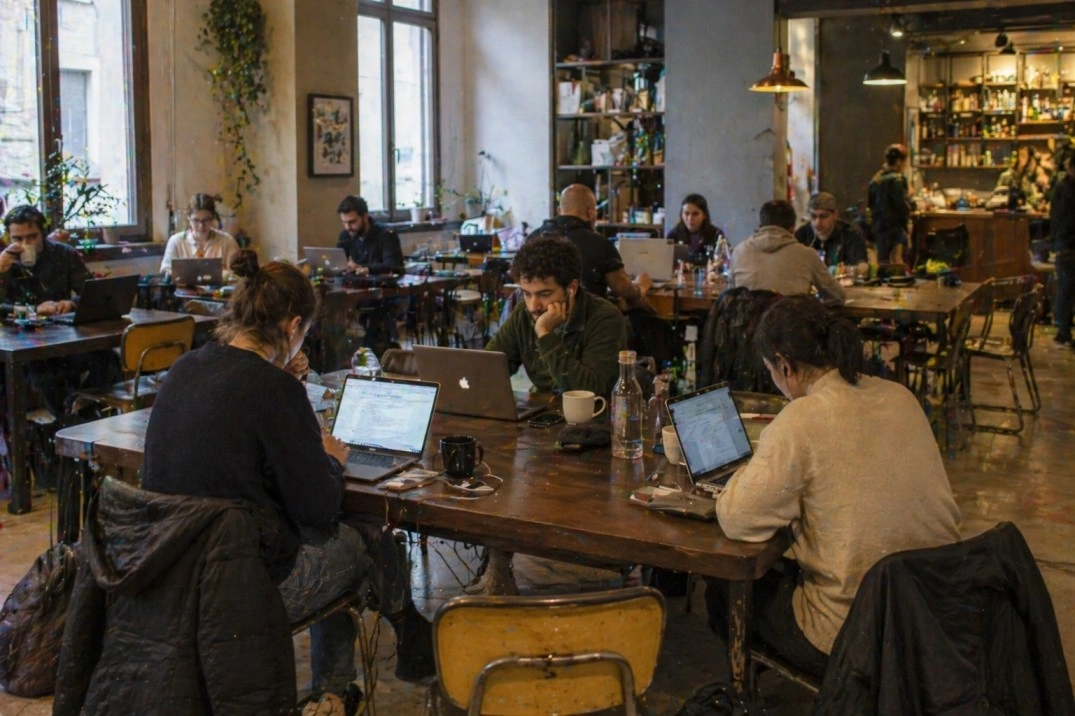 Remote work in Bologna, Italy – people working on laptops in a realistic café or coworking space