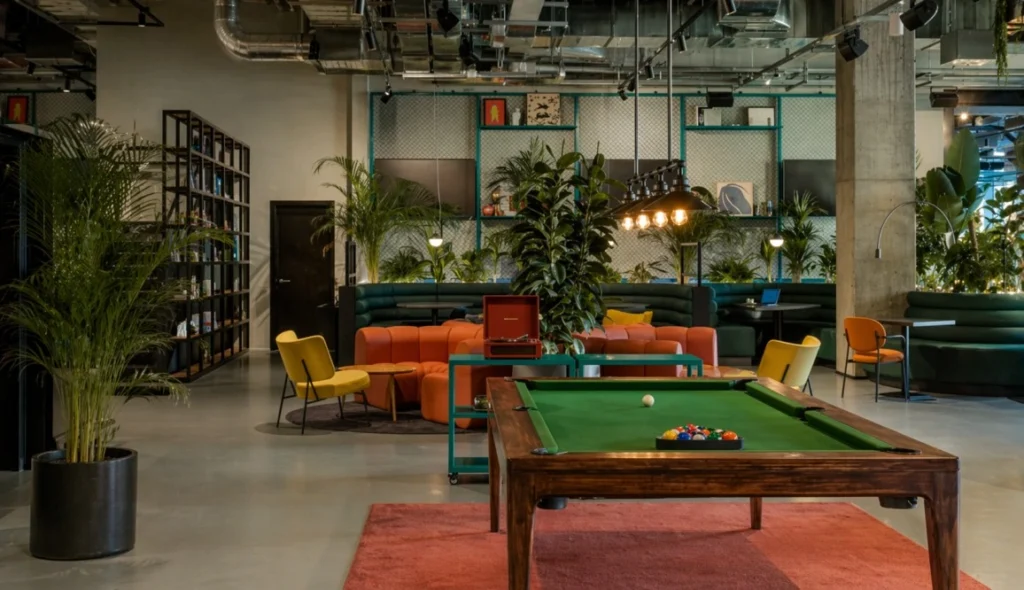 The Social Hub Belfiore Florence coliving and coworking lounge with pool table, seating area and plants