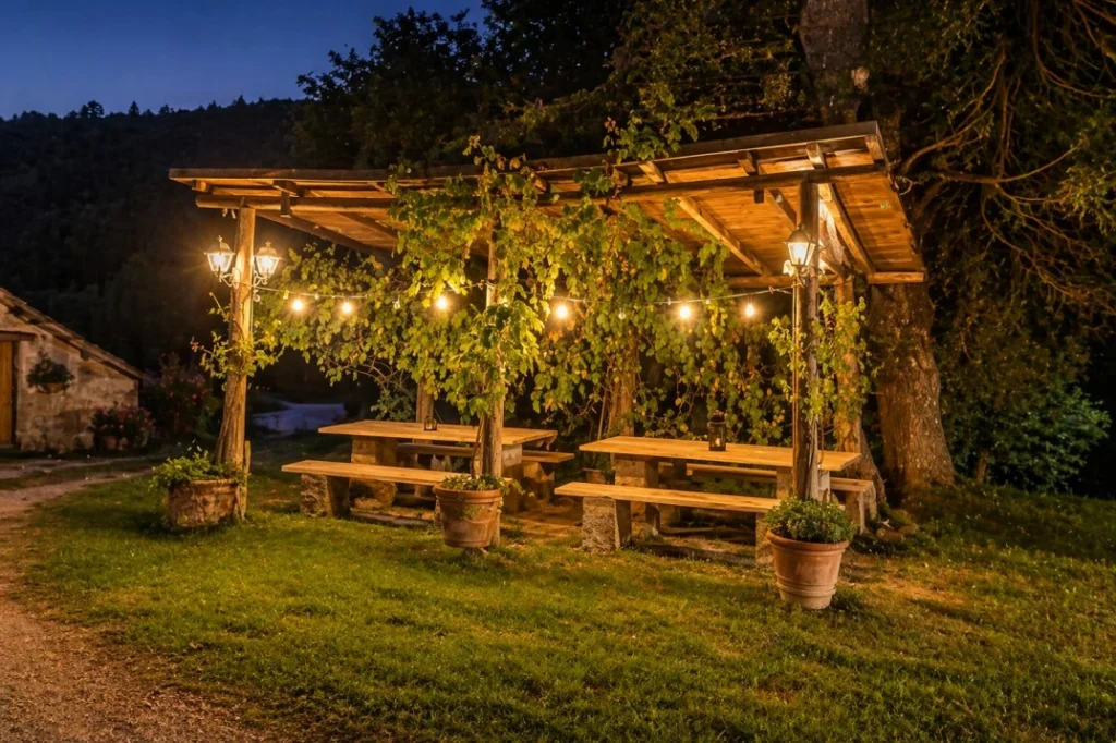 Rustic outdoor dining pergola at Tuscany Time in Tuscany with warm evening lights and shared community seating
