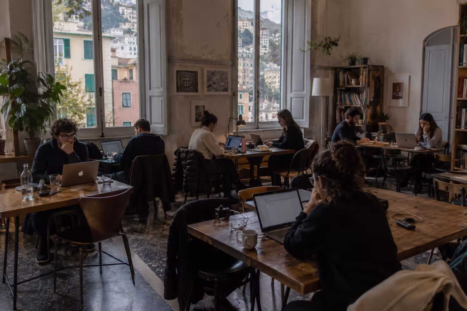 Remote work in Genova, Italy – people working at laptops in a realistic shared workspace